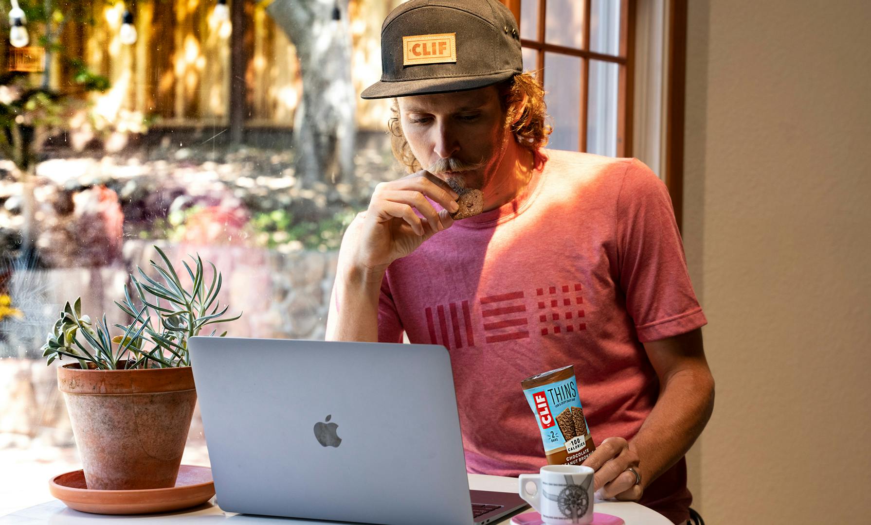 Athlete eating CLIF Thins Using Computer